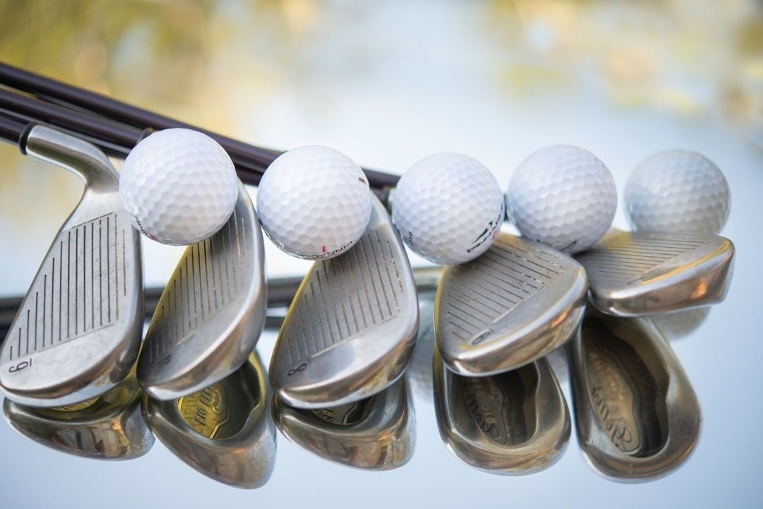 Fem golfklubbor med vita golfbollar, arrangerade på en blank yta